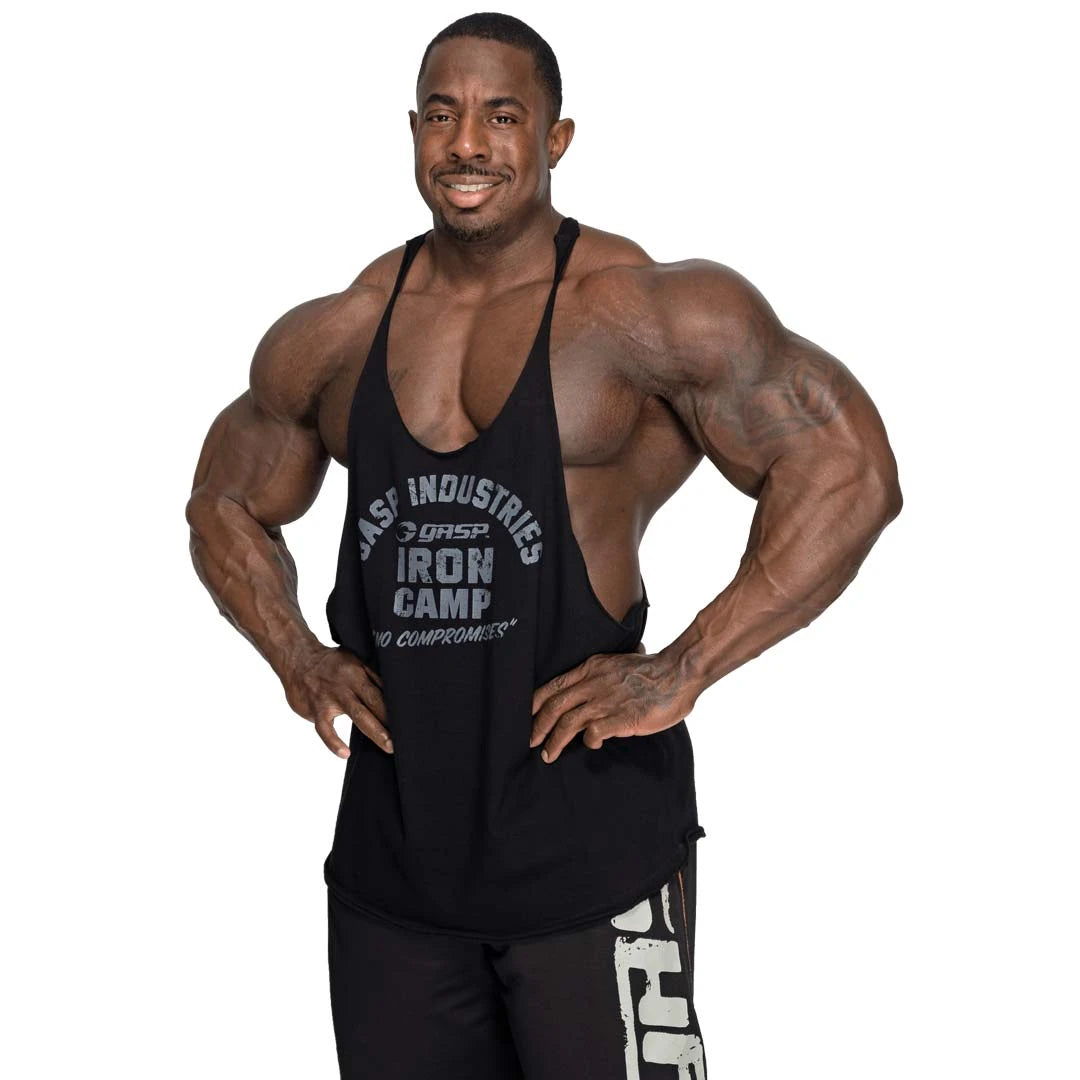 GASP Stringer Tank Black, ett svart träningslinne i bomull med tryck framtill, buret av en muskulös man.
