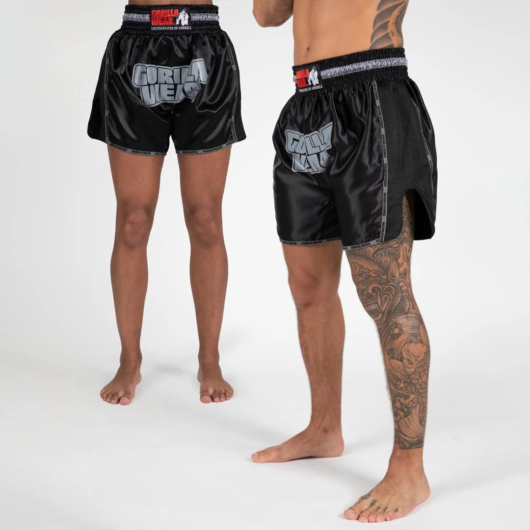 Gorilla Wear Piru Muay Thai Shorts black -mustat kamppailushortsit isolla logolla ja verkkosivuhalkioilla.