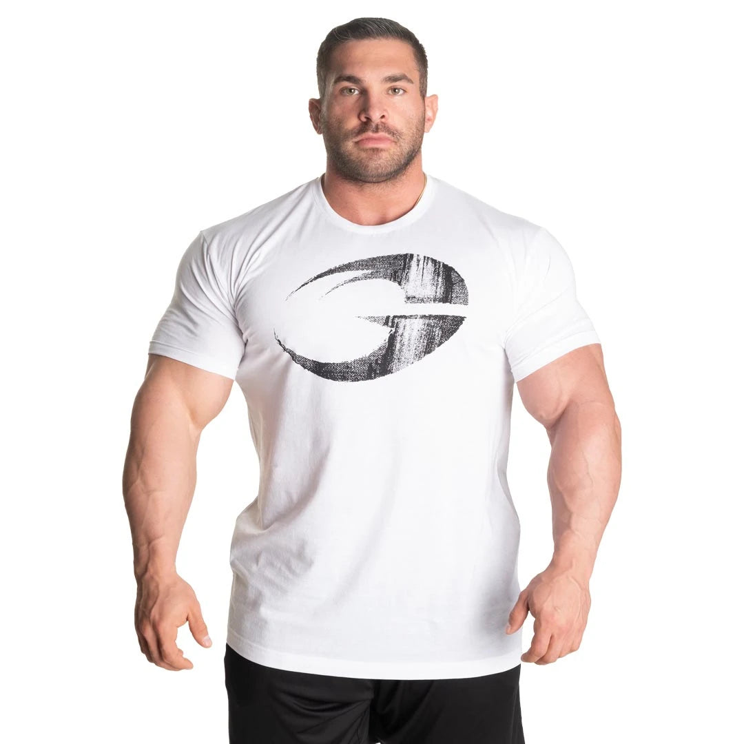 GASP Cadet Tee White, valkoinen miesten t-paita kulutetulla mustalla logopainatuksella lihaksikkaan miehen yllä.