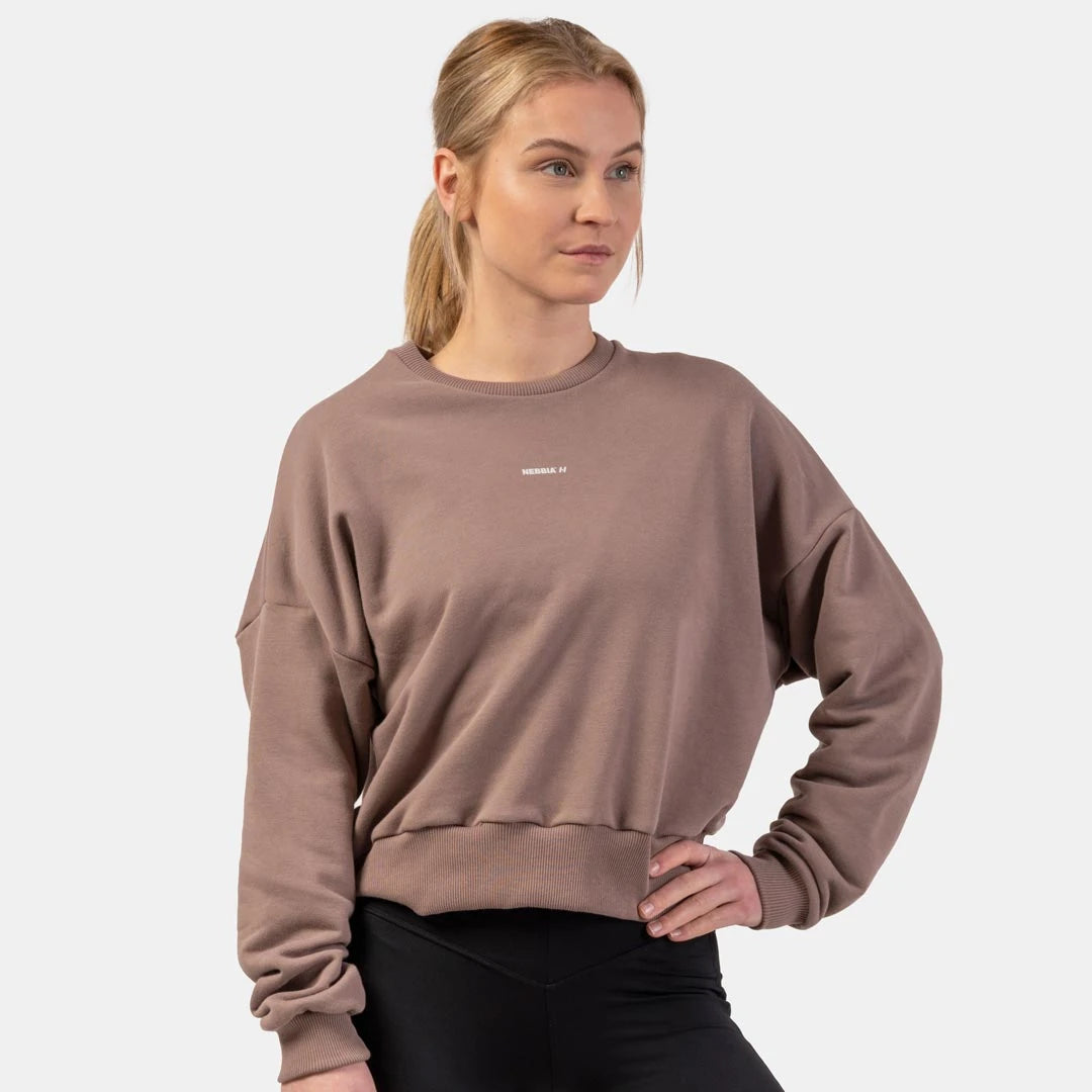 NEBBIA Loose Fit Sweatshirt Feeling Good Brown, ruskea väljän mallinen treenipaita leveillä resoreilla naisen yllä.