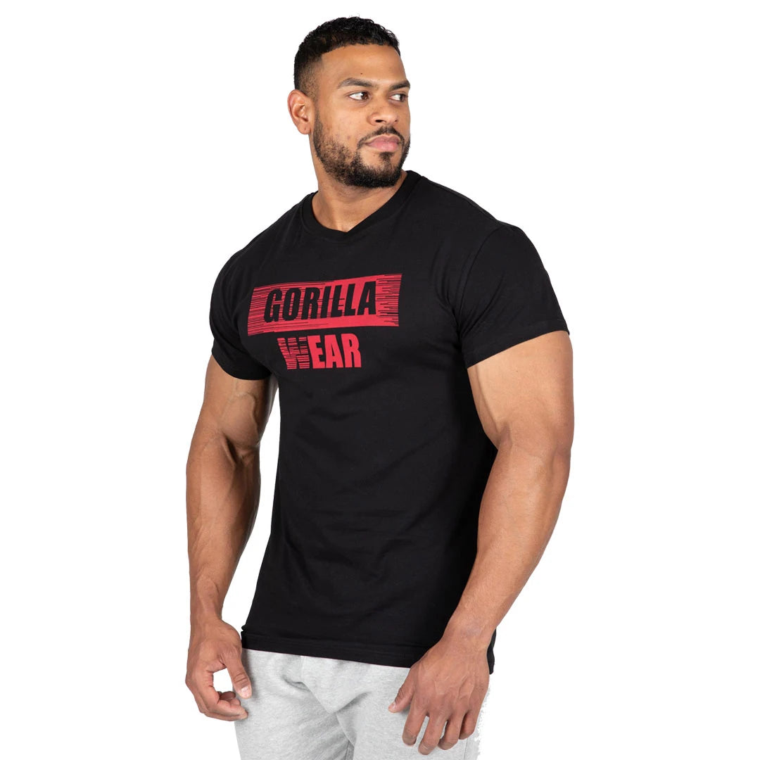 Gorilla Wear Murray T-Shirt Black, musta puuvillainen slim fit -paita punaisella logopainatuksella miehen yllä.