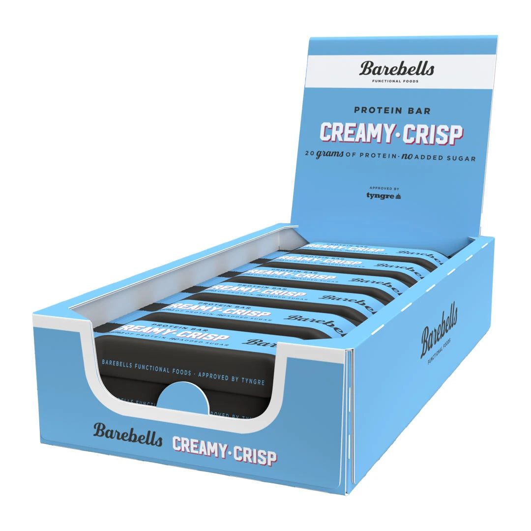 12 x Barebells Protein Bar 55 g Creamy Crisp vaaleansinisessä laatikossa, joka on täytetty mustilla ja sinisillä proteiinipatukoilla., kuva 1/1