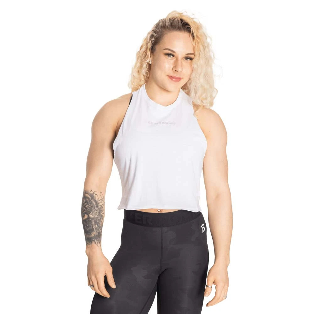 Kvinna klädd i Better Bodies Fluid Loose Racerback White, ett vitt och croppat träningslinne med lös passform.
