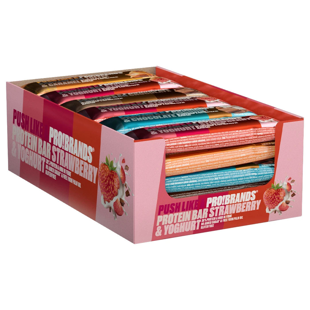 24 x Pro Brands Proteinbar 45 g Mixpack vaaleanpunaisessa laatikossa, joka on täytetty erimakuisilla proteiinipatukoilla.