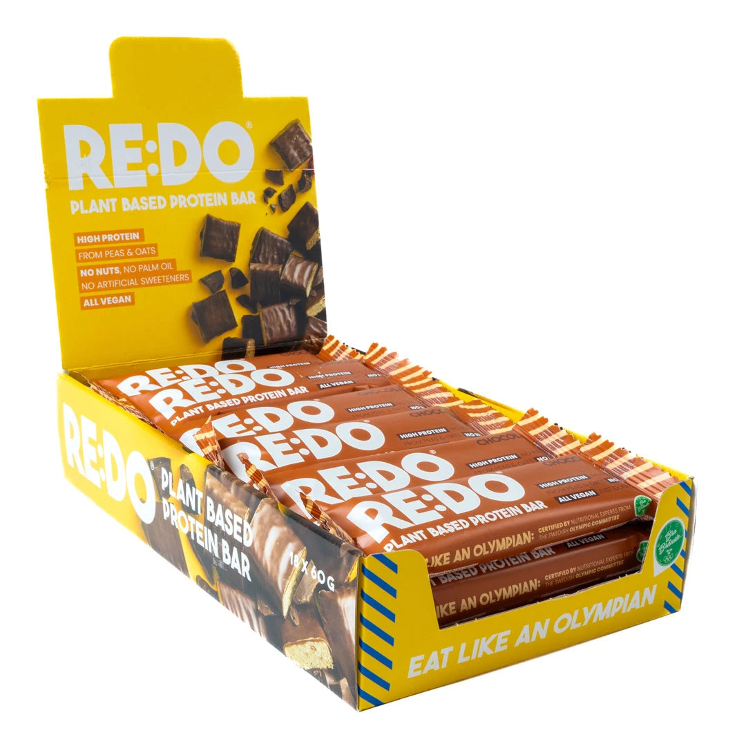 18 x REDO Bar 60 g Chocolate Chock avoimessa keltaisessa esittelylaatikossa täynnä ruskeita proteiinipatukoita., kuva 1/1