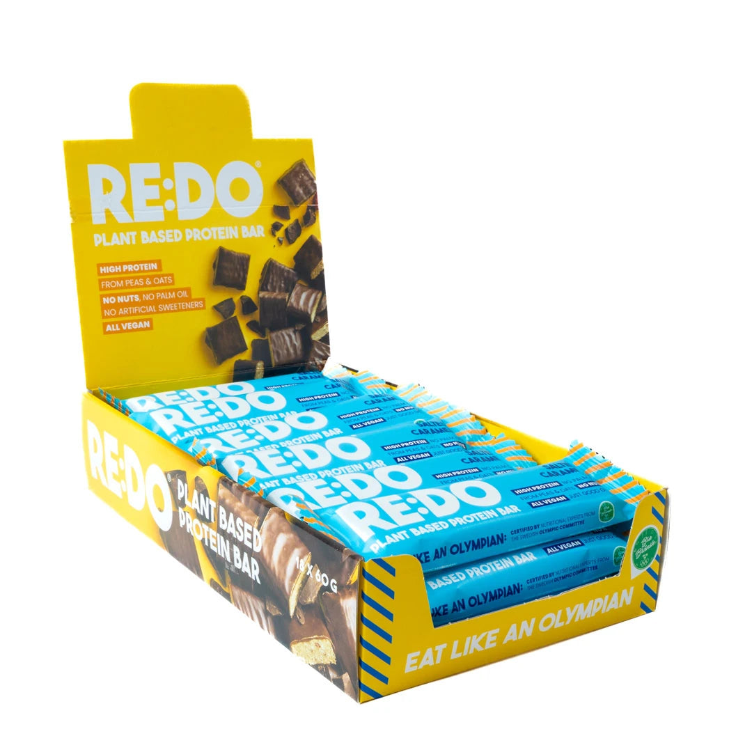 18 x REDO Bar 60 g Salty Caramel -proteiinipatukoita sinisissä kääreissä keltaisessa esittelylaatikossa., kuva 1/1
