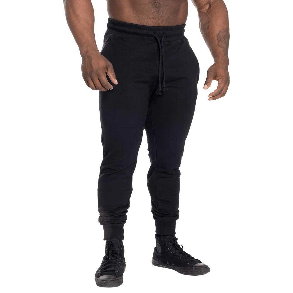 GASP Tapered Joggers Black -mustat treenihousut kapenevalla lahkeella ja vyötärönauhalla mallin yllä.