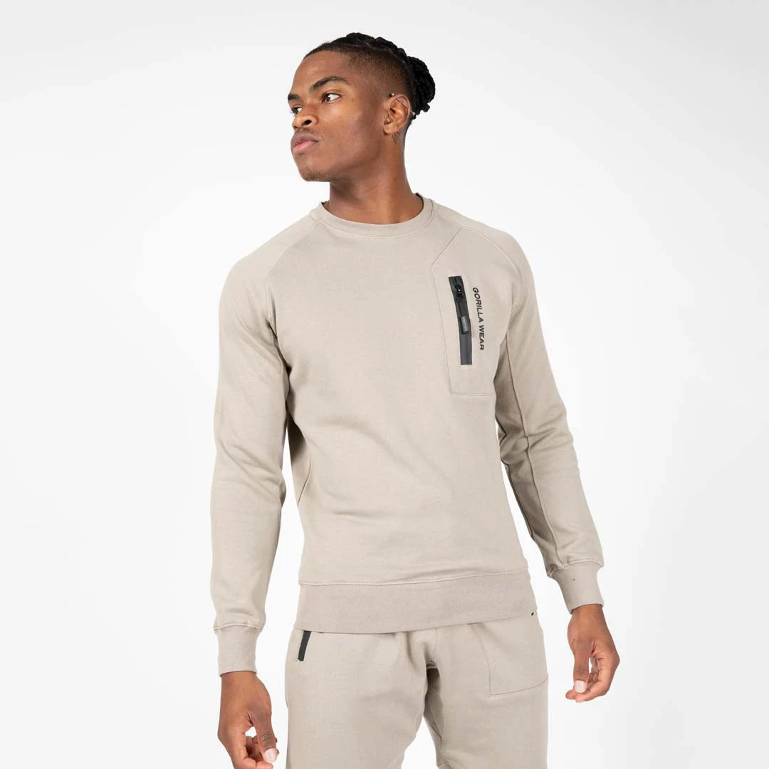 Miesmalli yllään Gorilla Wear Newark Sweater Beige, rento puuvillapaita mustalla vetoketjullisella rintataskulla.